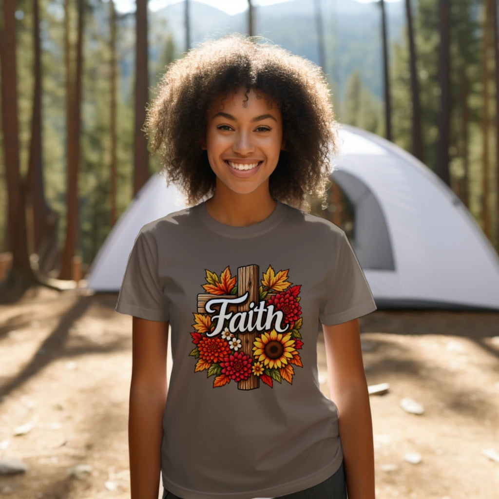 Young Black woman wearing a Heather Brown Autumn Faith floral cross T-shirt at a wooded campsite with a tent in the background.
